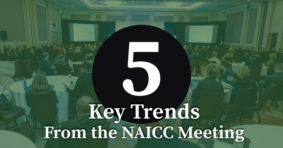 Conference audience at NAICC meeting in large ballroom with presentation screens showing data charts and key trends overview, professionals networking and attending industry session